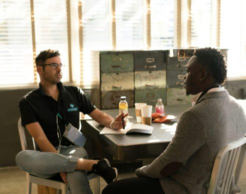 Two men having a focused business discussion in a sunlit office space.